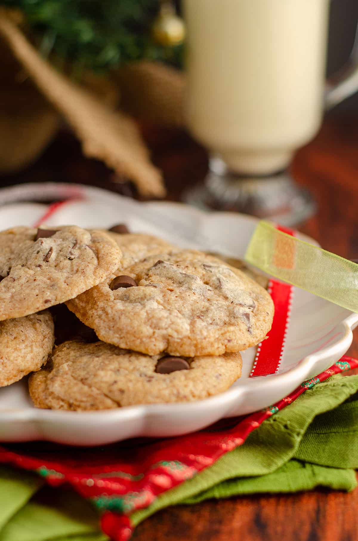 eggnog chocolate chunk cookies sitting on a plate with christmas ribbons around it