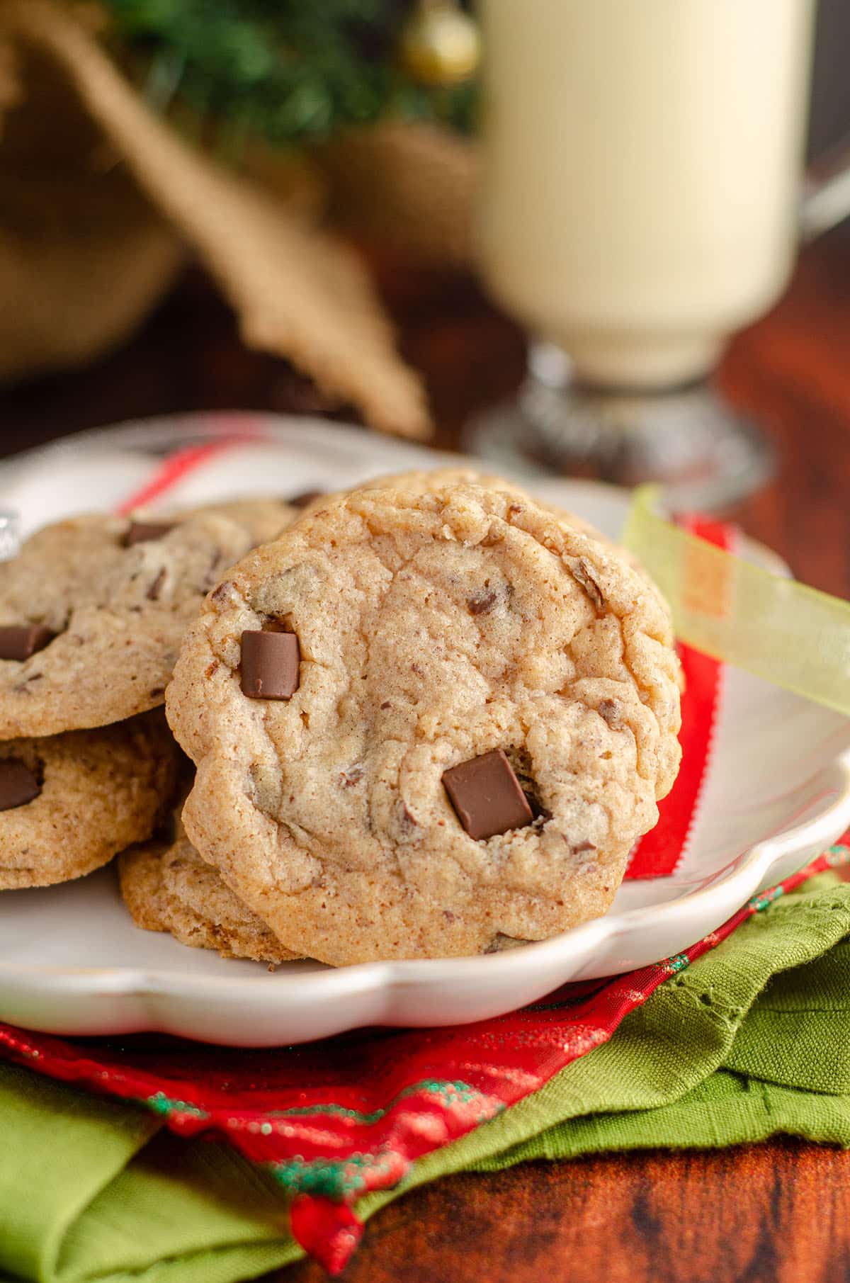 eggnog chocolate chunk cookies sitting on a plate with christmas ribbons around it