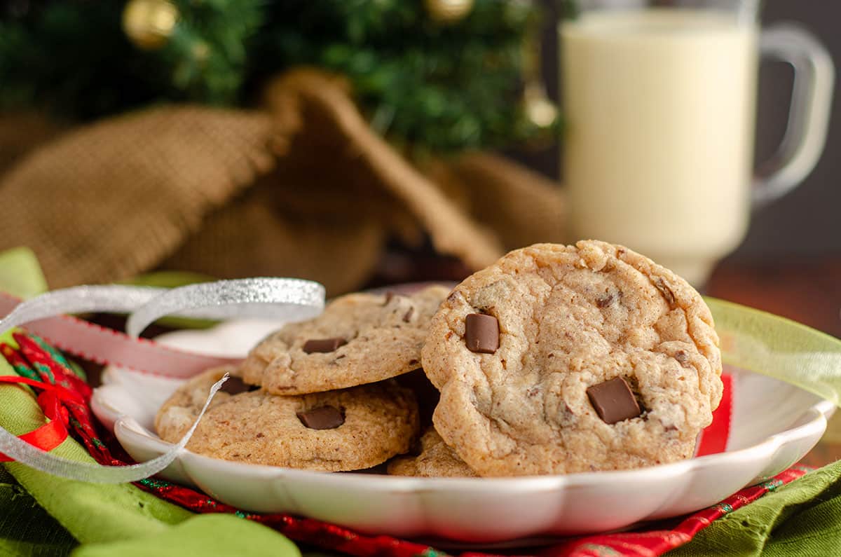 eggnog chocolate chunk cookies sitting on a plate with christmas ribbons around it