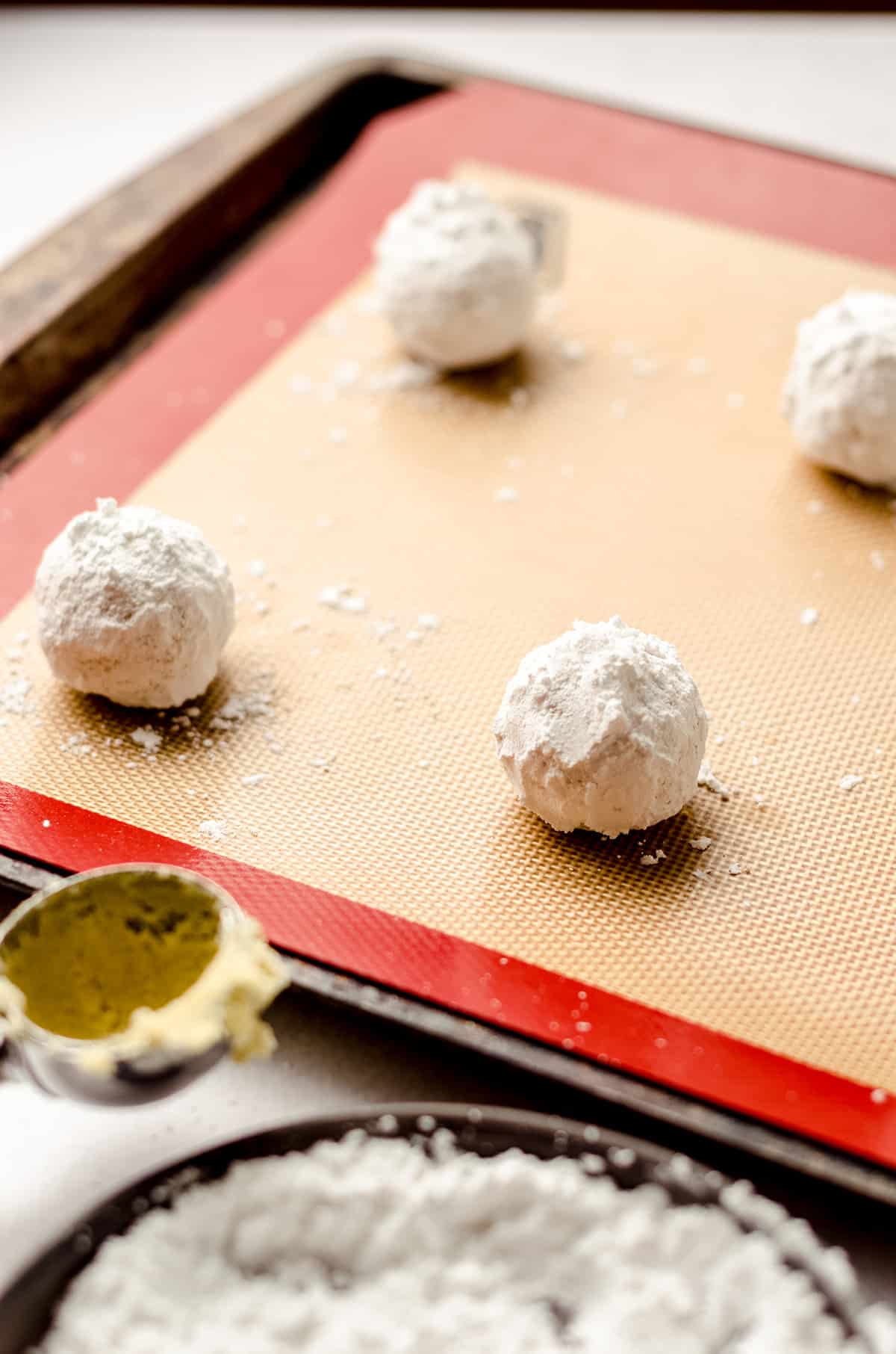lemon crinkle cookie dough balls coated in powdered sugar on a baking sheet