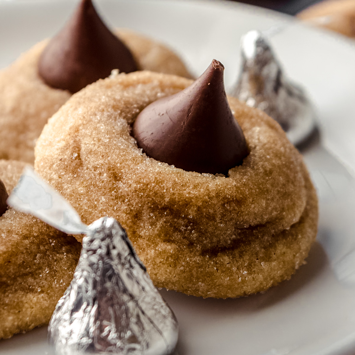 A plate of peanut butter blossoms with Hershey's Kisses around it.