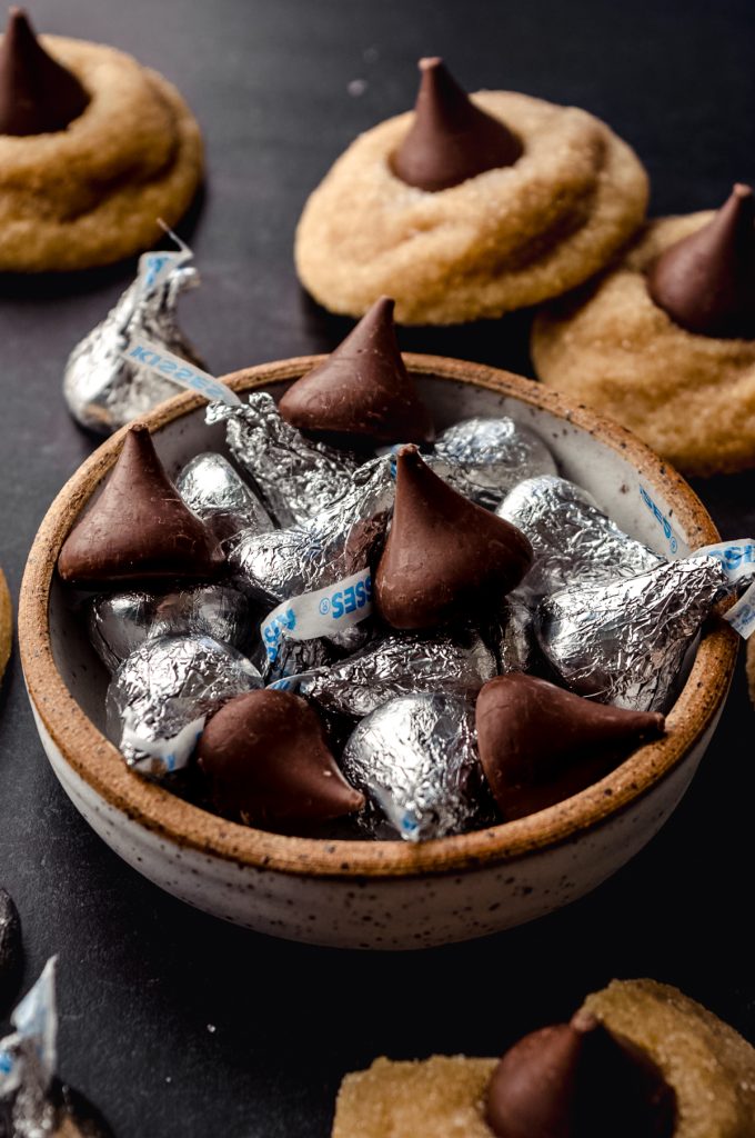 A bowl of Hershey's Kisses and some have been unwrapped.