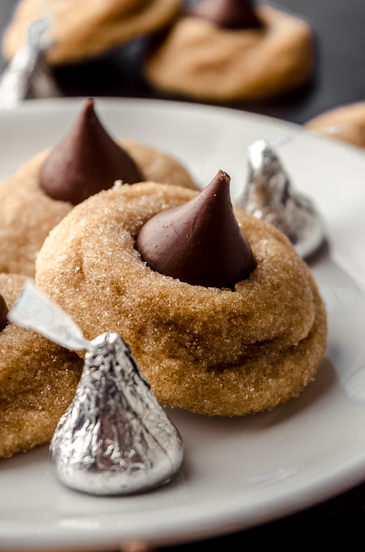A plate of peanut butter blossoms with Hershey's Kisses around it.