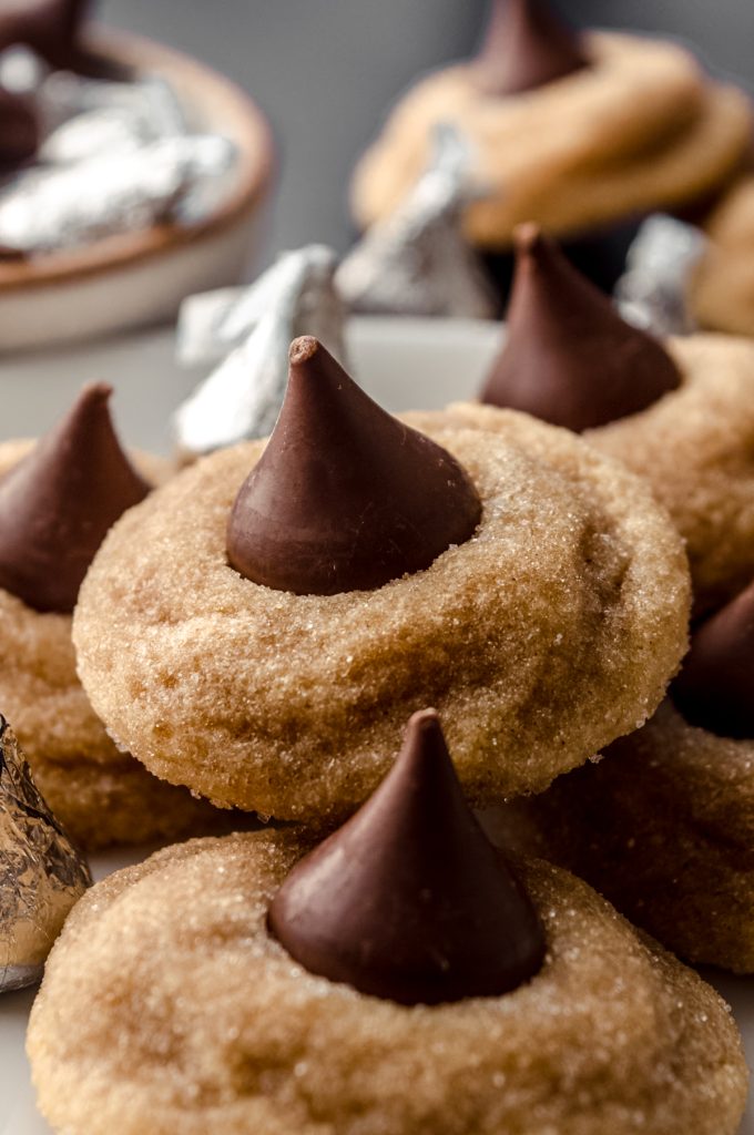 A plate of peanut butter blossoms with Hershey's Kisses around it.