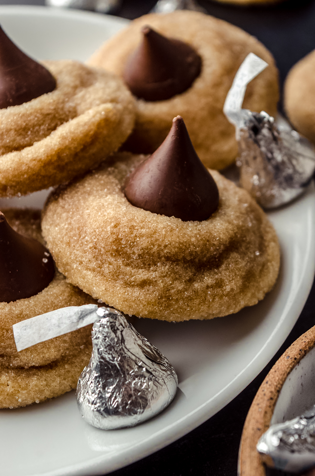 A plate of peanut butter blossoms with Hershey's Kisses around it.