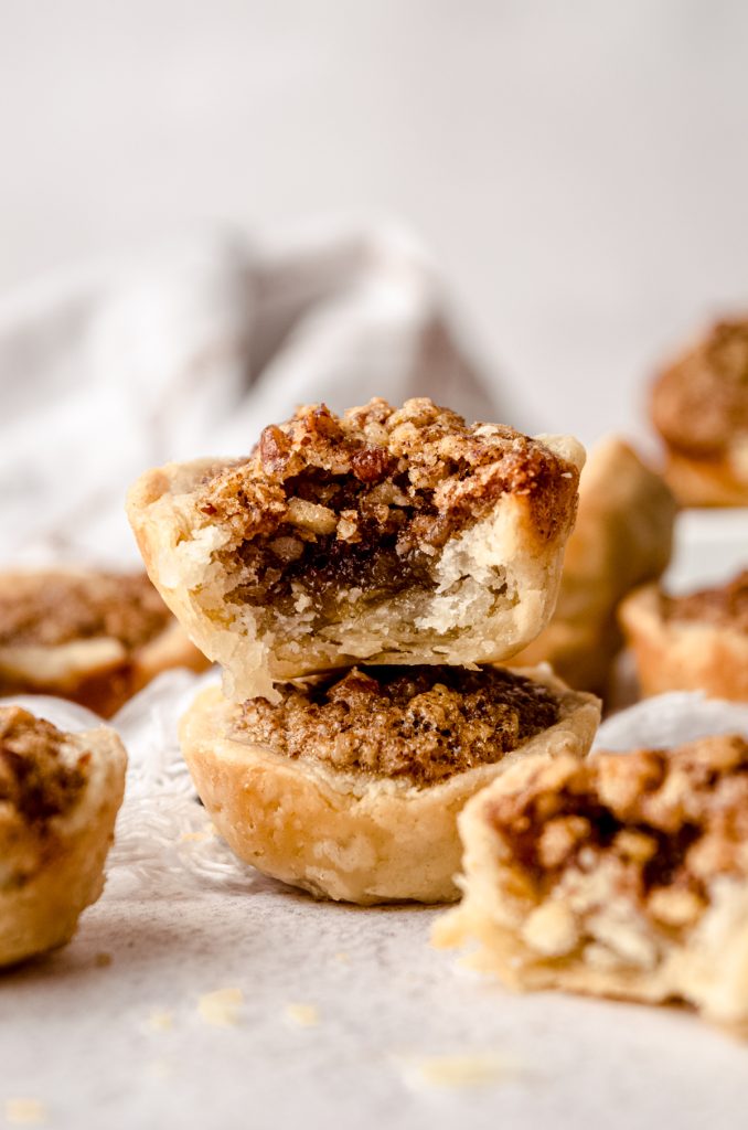 A stack of two pecan tassies and a bite has been taken out of the one on the top.