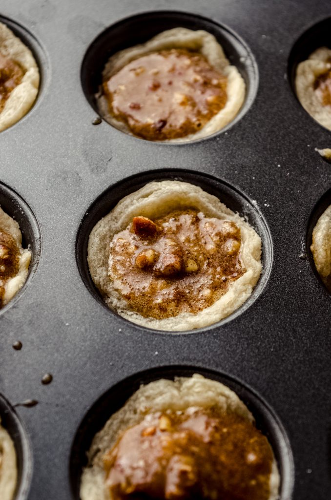 Unbaked pecan tassies in a baking pan.