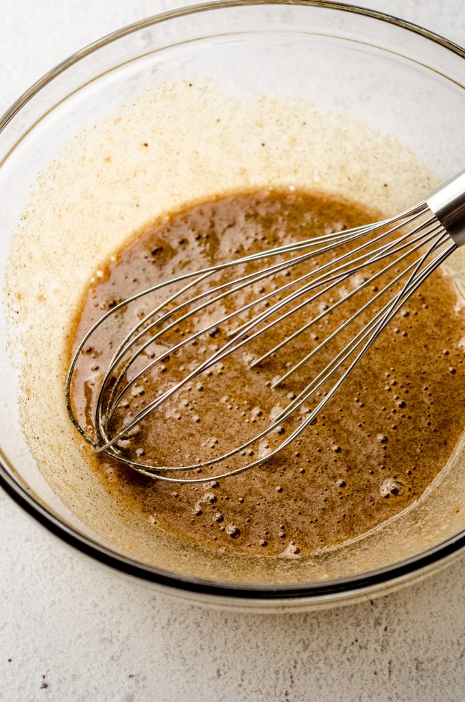 Pecan pie tart filling in a large glass bowl with a whisk.