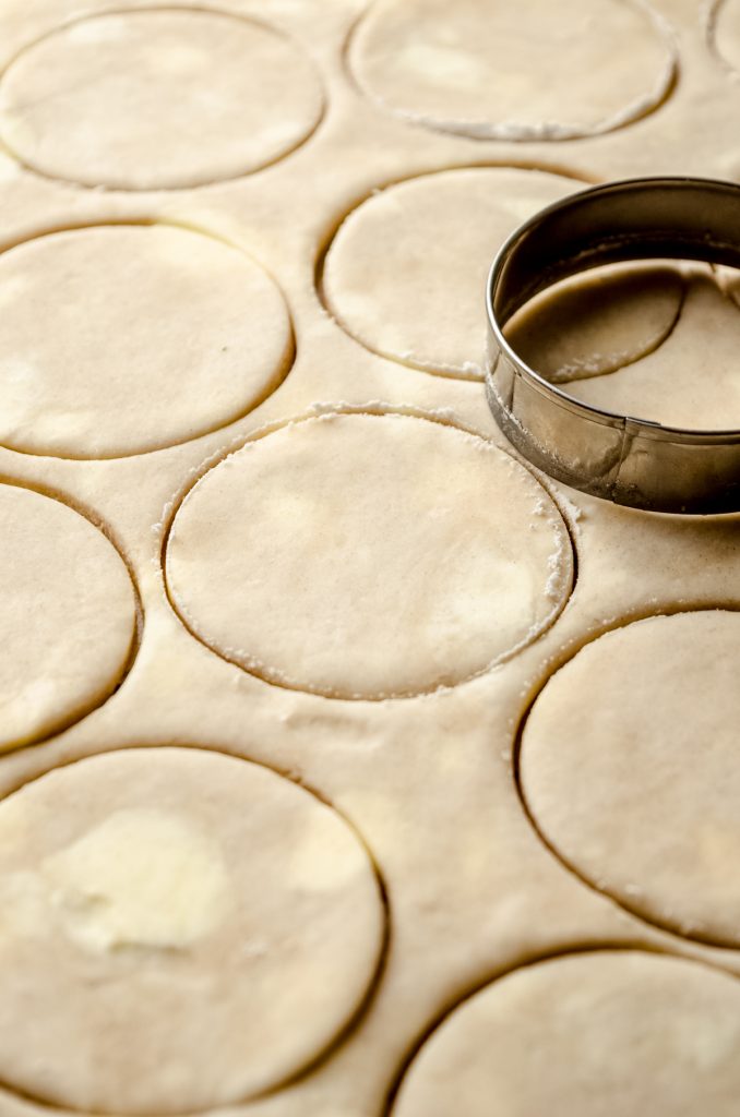 Pie dough cut into circles with a round cookie cutter to make pecan pie tarts.