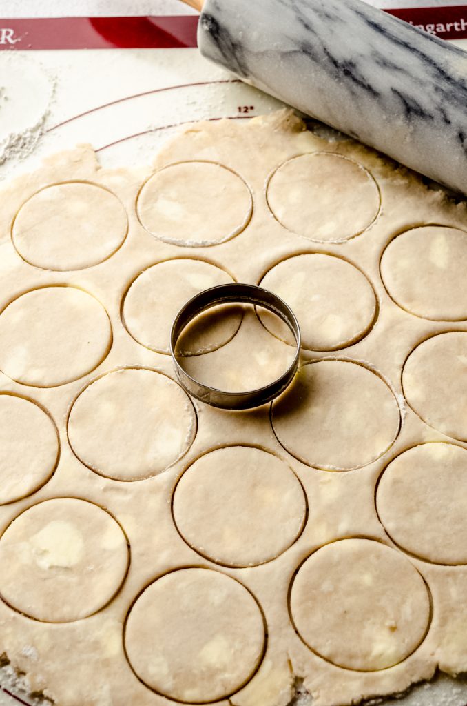 Pie dough cut into circles with a round cookie cutter to make pecan tassies.