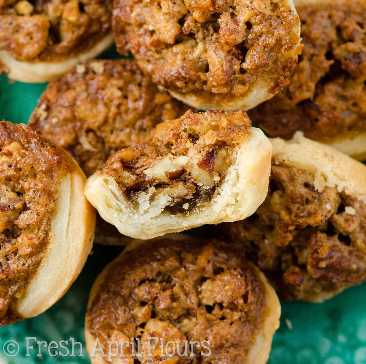 Pecan pie tarts on a plate with a bite taken out of one of them. 