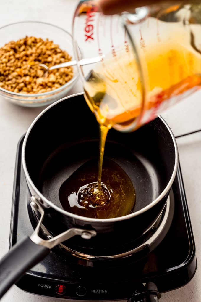 Someone is pouring honey into a saucepan.