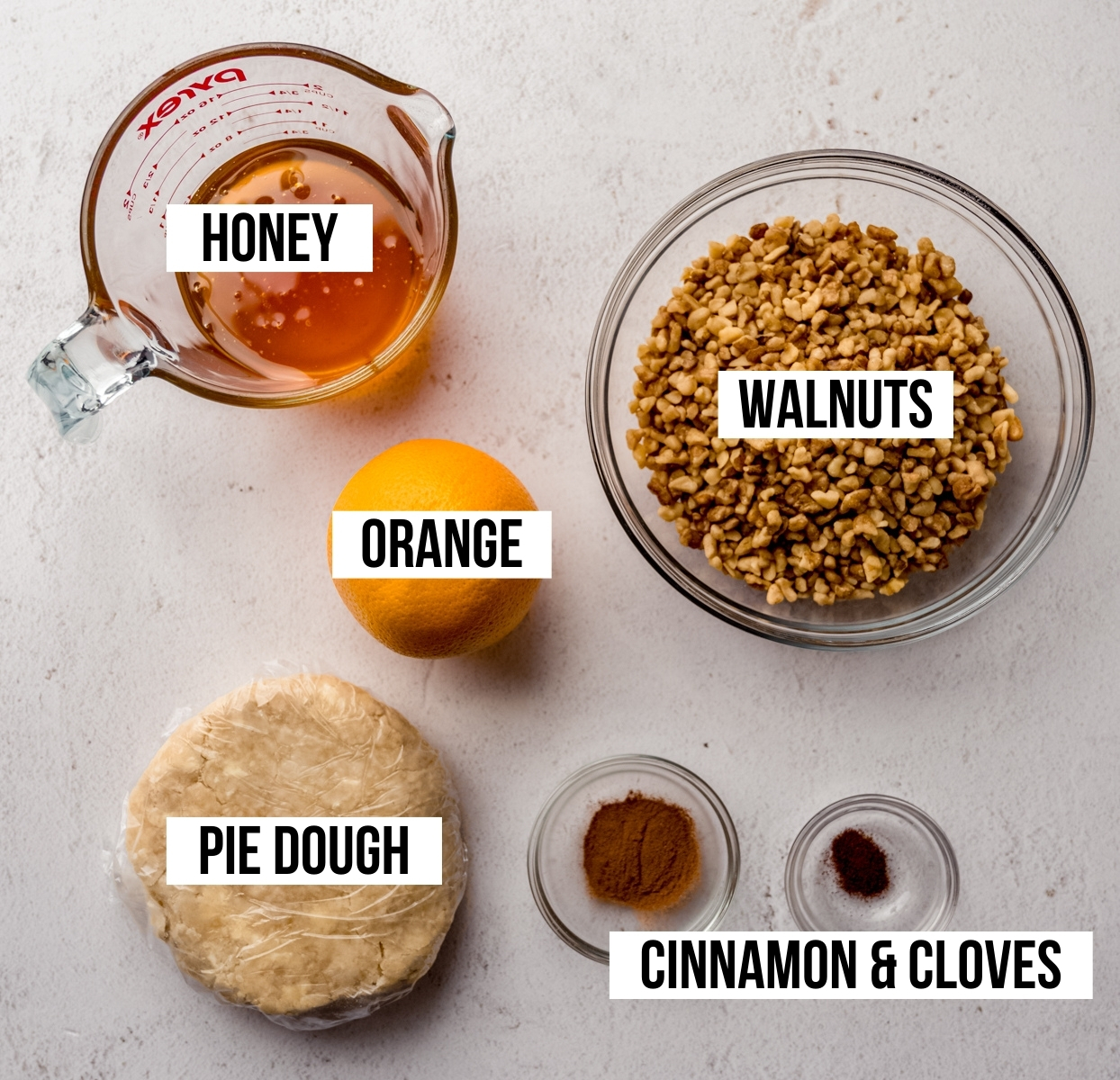 Aerial photo of ingredients to make honey walnut cookie sticks (sfratti) with text overlay labeling each ingredient.