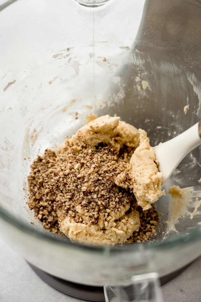 Russian tea cake cookie dough in the bowl of a mixer with a spatula.