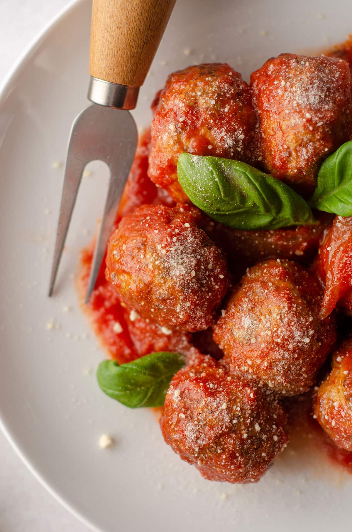 aerial photo of gluten free meatballs on a plate with basil leaves and a serving fork