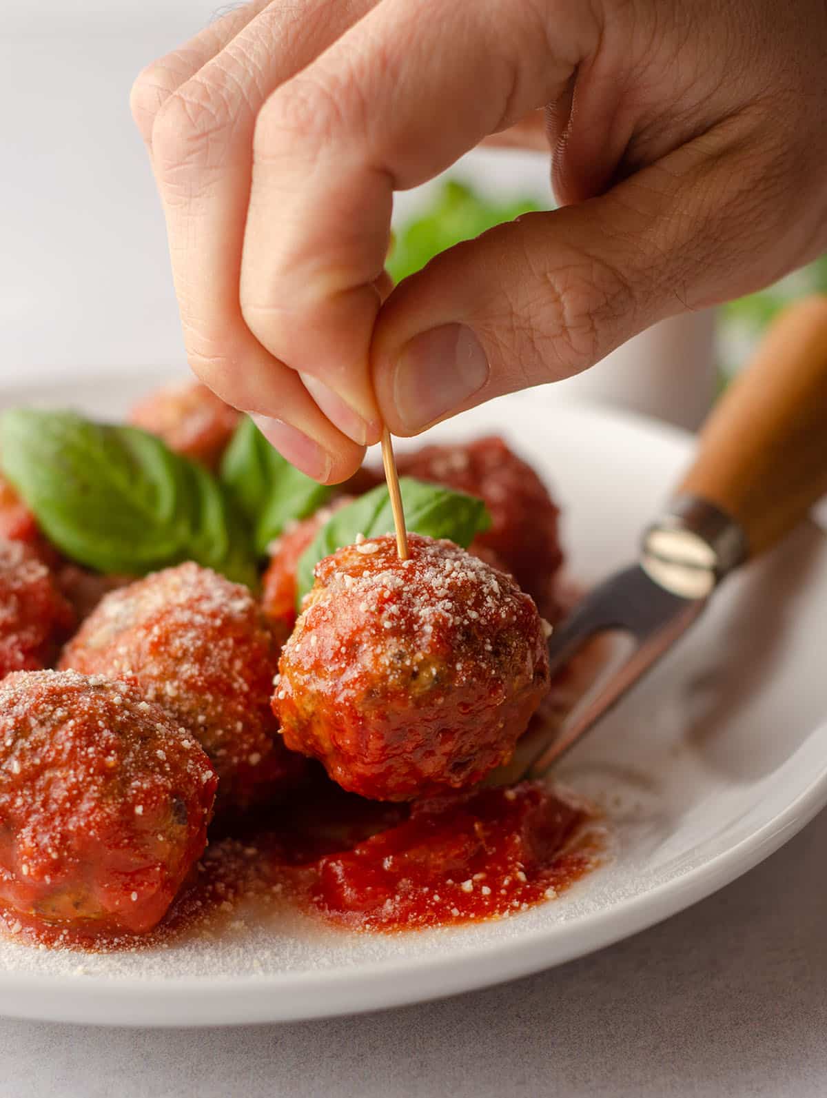 hand sticking a toothpick into a gluten free meatball