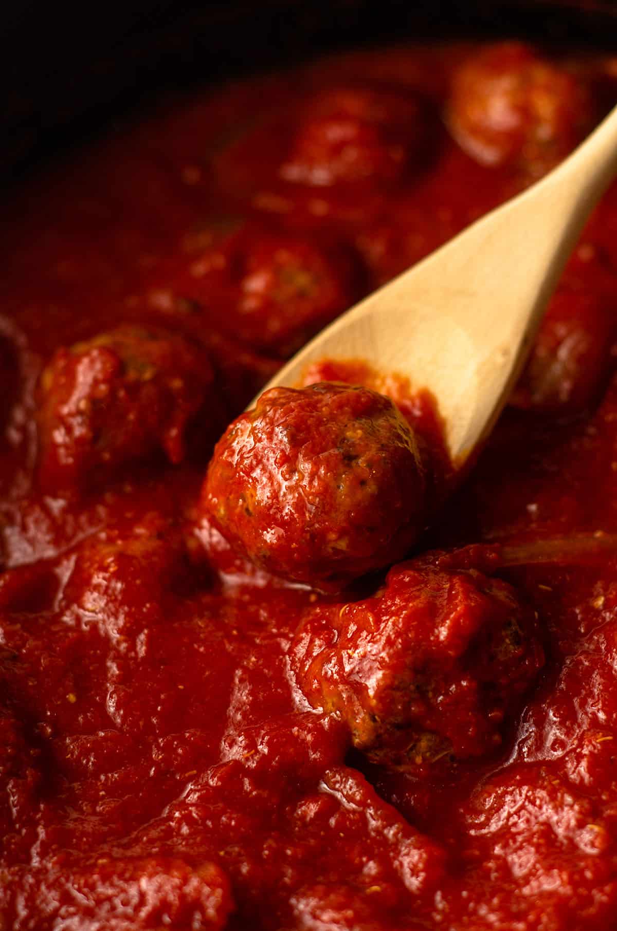 gluten free meatballs in a slow cooker with a wooden spoon