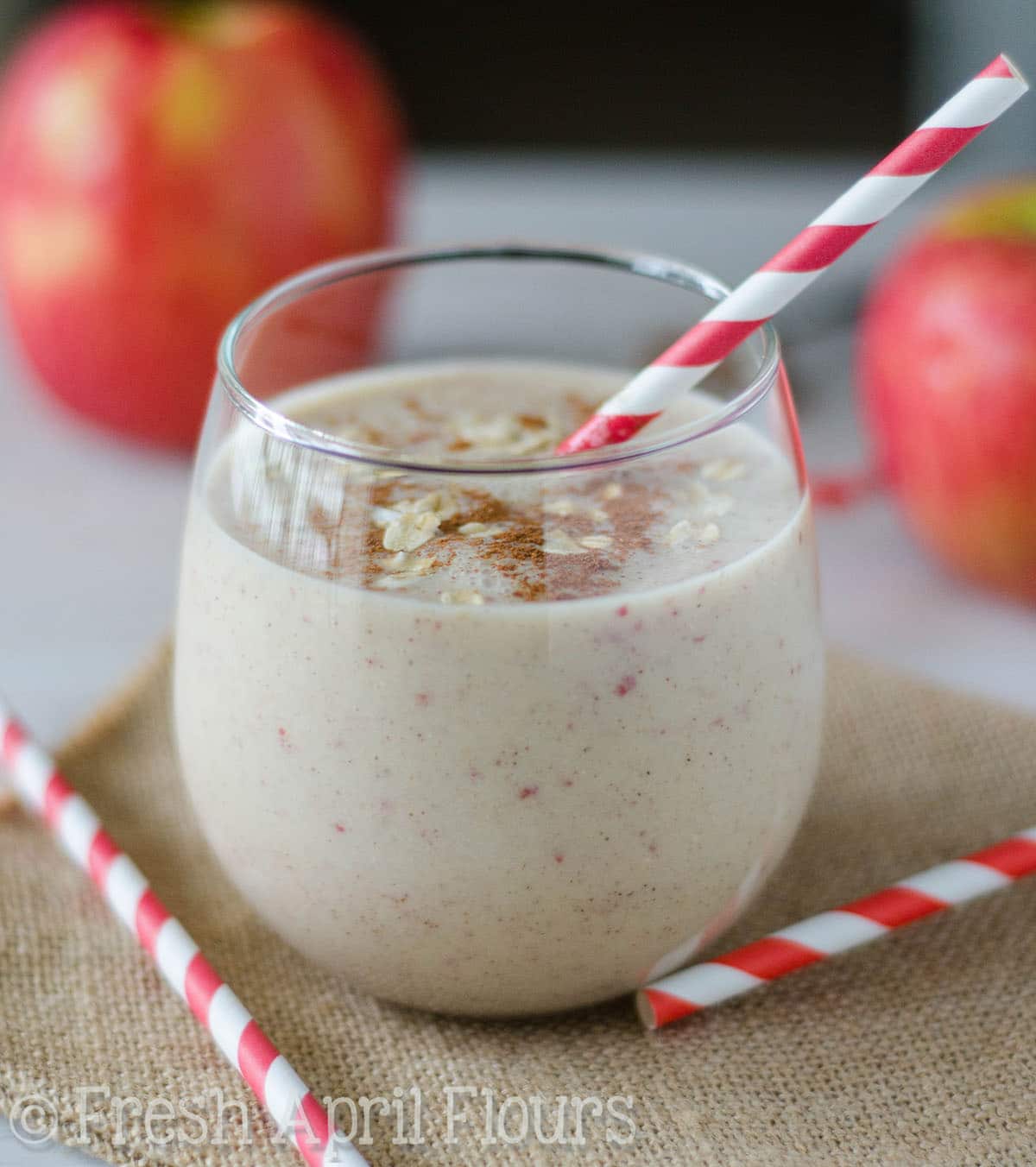 An apple pie smoothie in a glass with a straw.