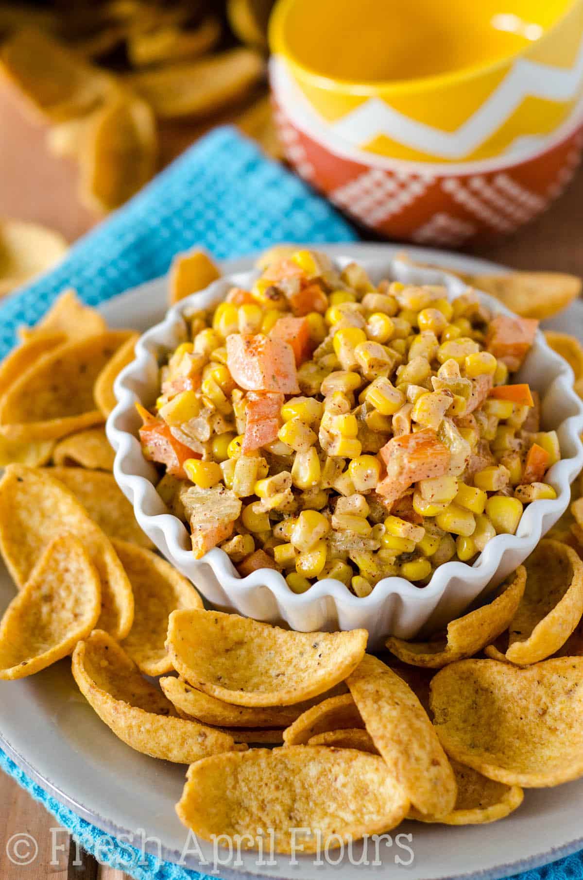 A bowl of southwest corn dip with corn chips around it.