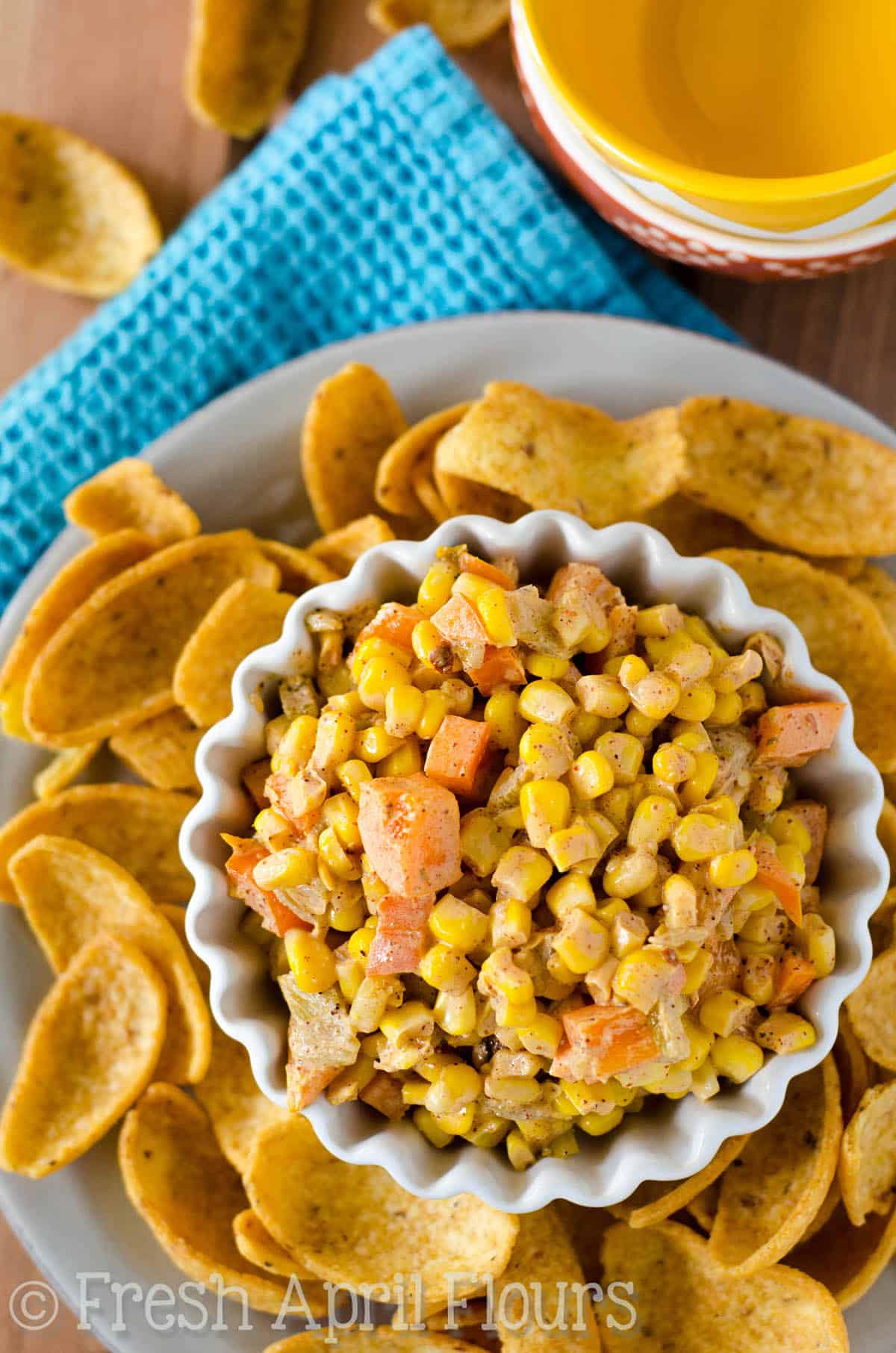 Aerial photo of southwest corn dip in a bowl on a plate with corn chips.