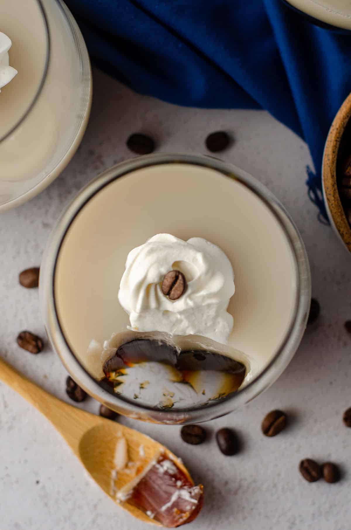 aerial photo of coffee jello in a cup with a dollop of whipped cream and a coffee bean on top
