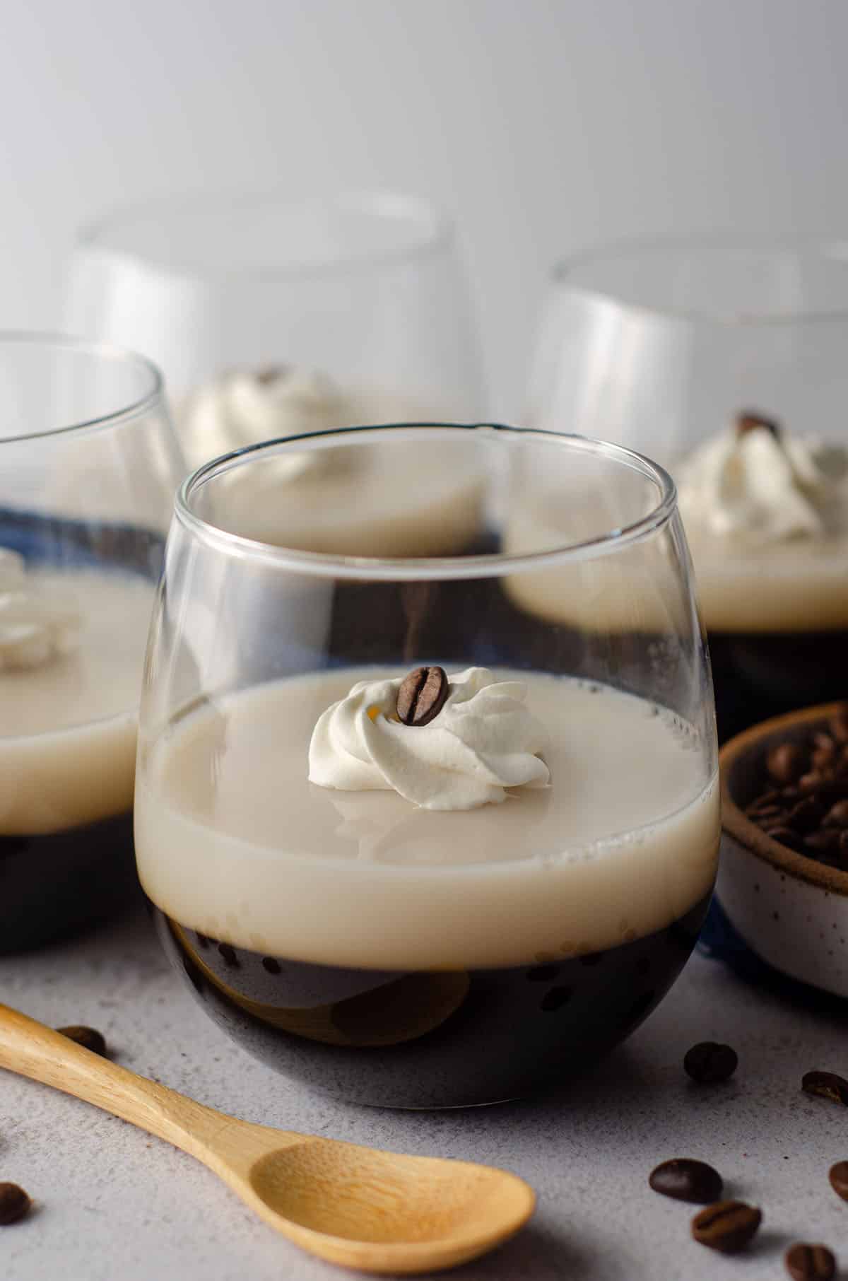 coffee jello in a cup with a dollop of whipped cream and a coffee bean on top