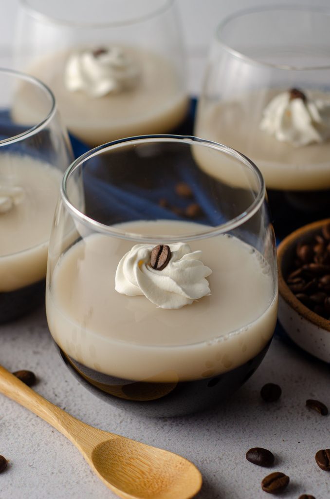 coffee jello in a cup with a dollop of whipped cream and a coffee bean on top