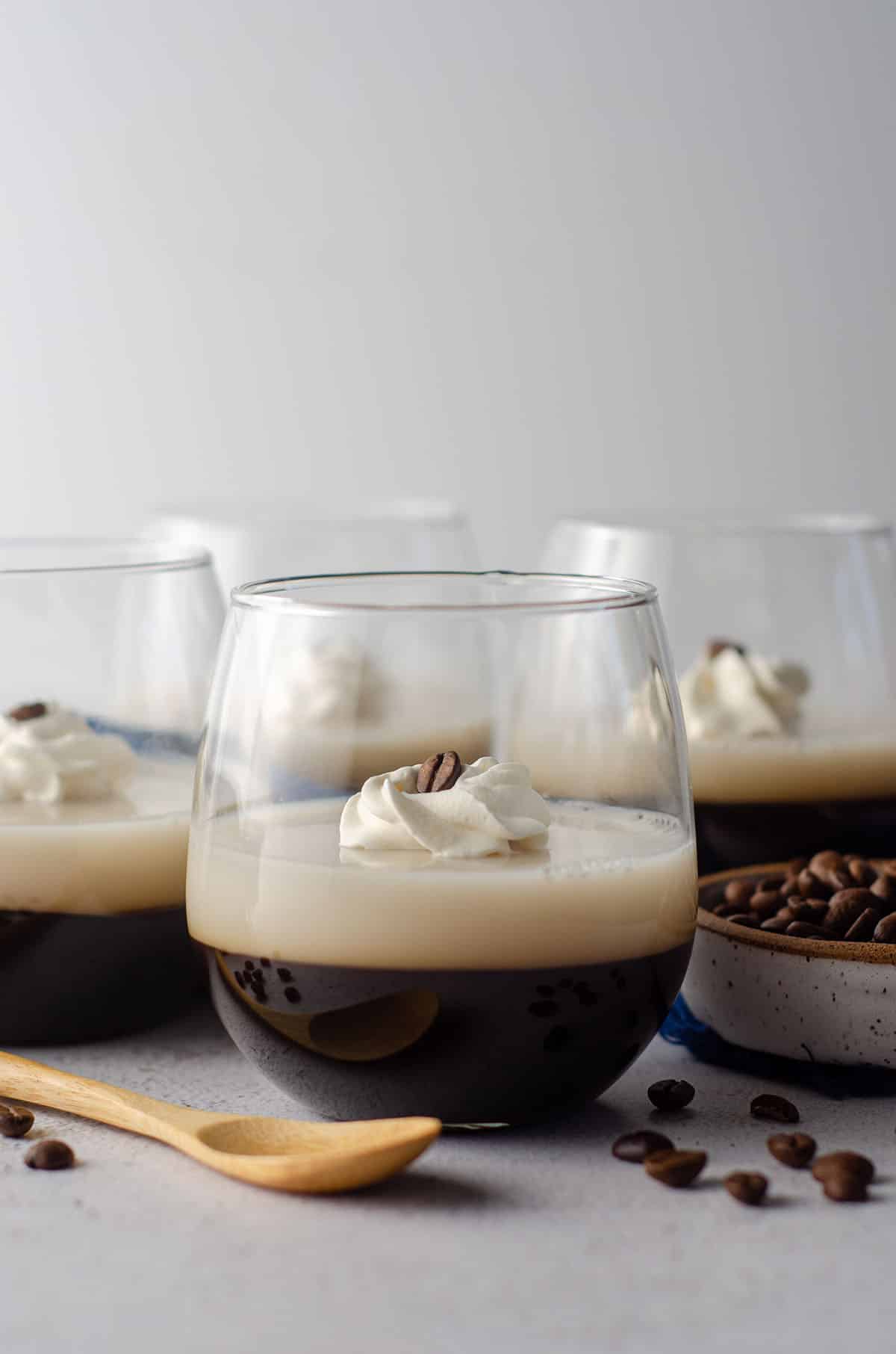 coffee jello in a cup with a dollop of whipped cream and a coffee bean on top