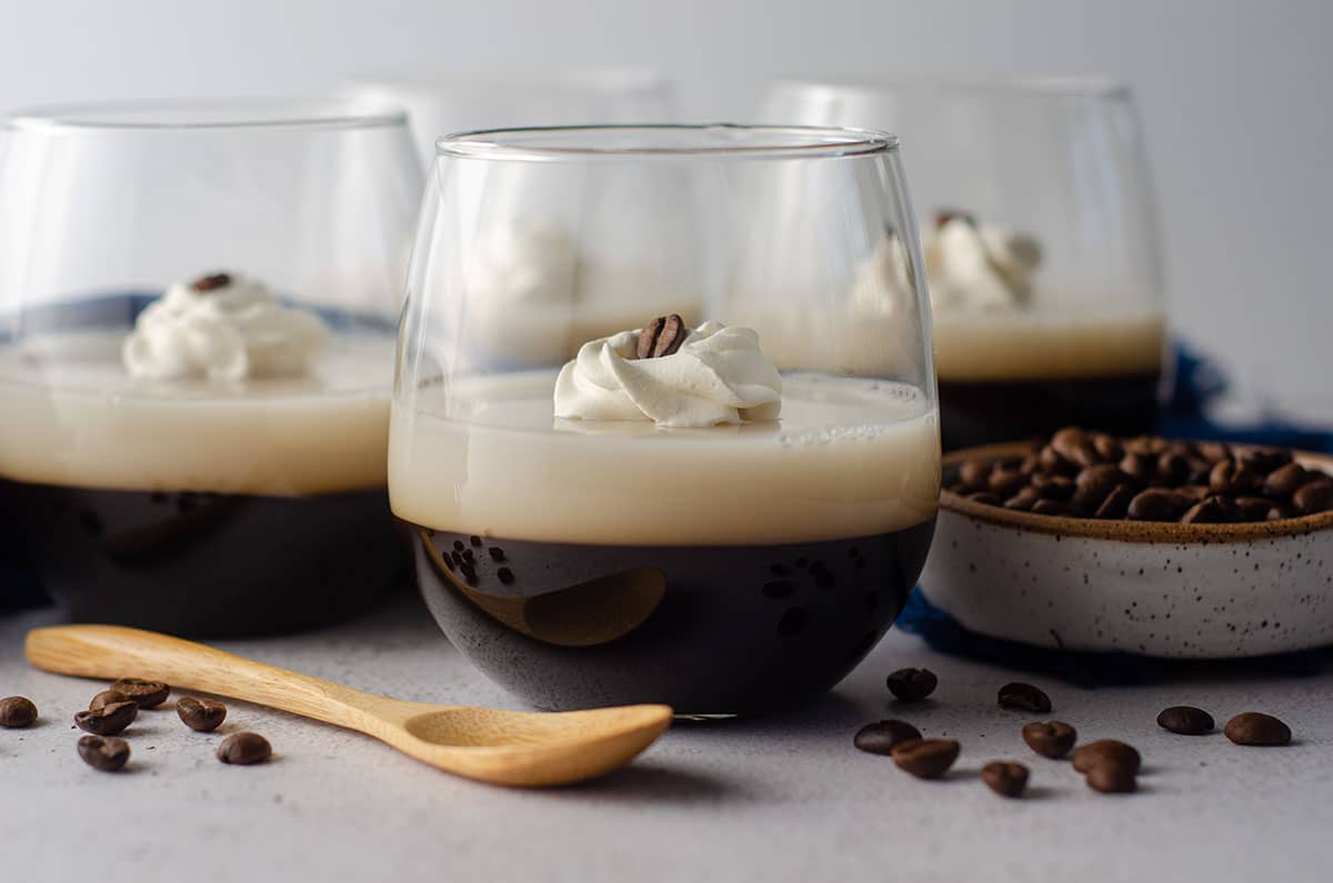coffee jello in a cup with a dollop of whipped cream and a coffee bean on top