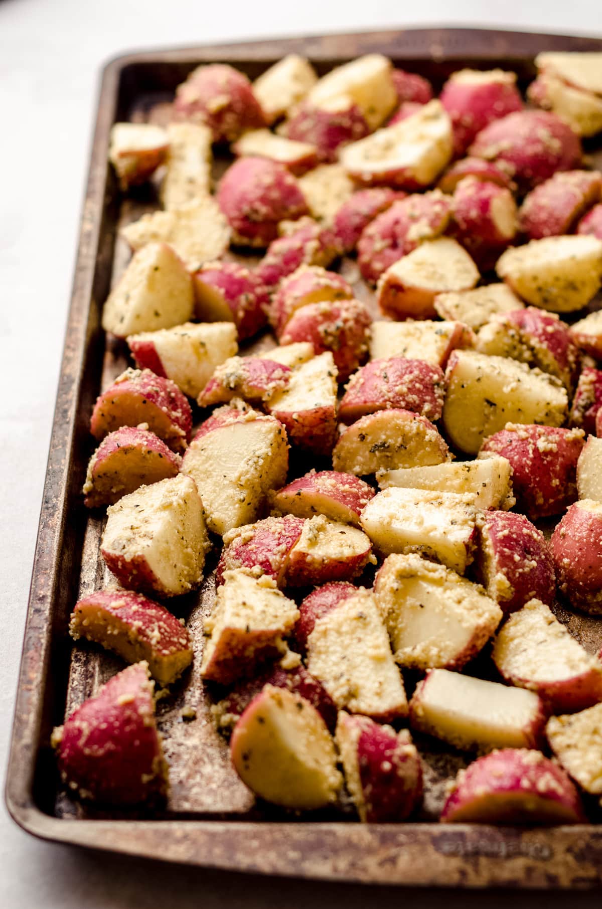 red potatoes on a baking sheet rubbed with cheese and herbs