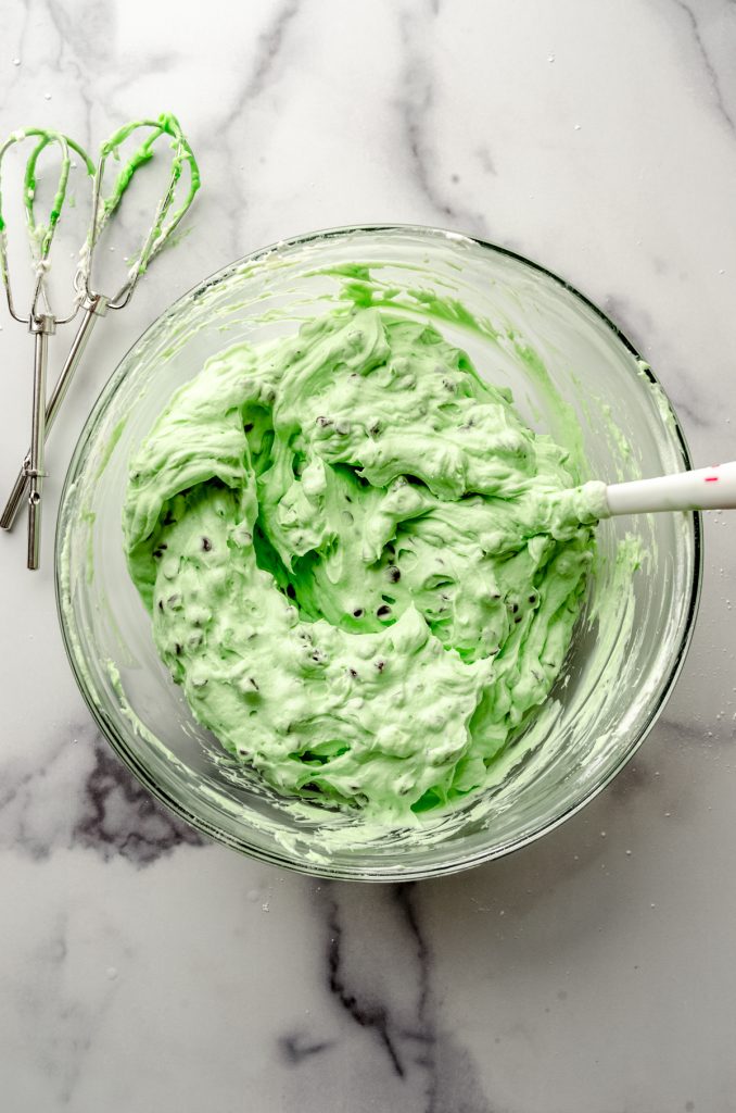 Aerial photo of a bowl of the filling for no bake mint chocolate chip pie with a spatula.