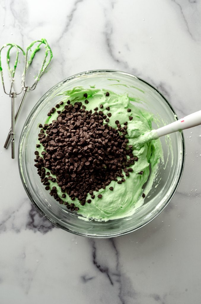 Aerial photo of a bowl of the filling for no bake mint chocolate chip pie with a spatula.