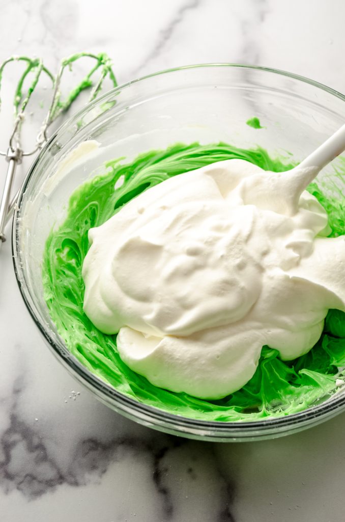 A bowl of the filling for no bake mint chocolate chip pie with a spatula.