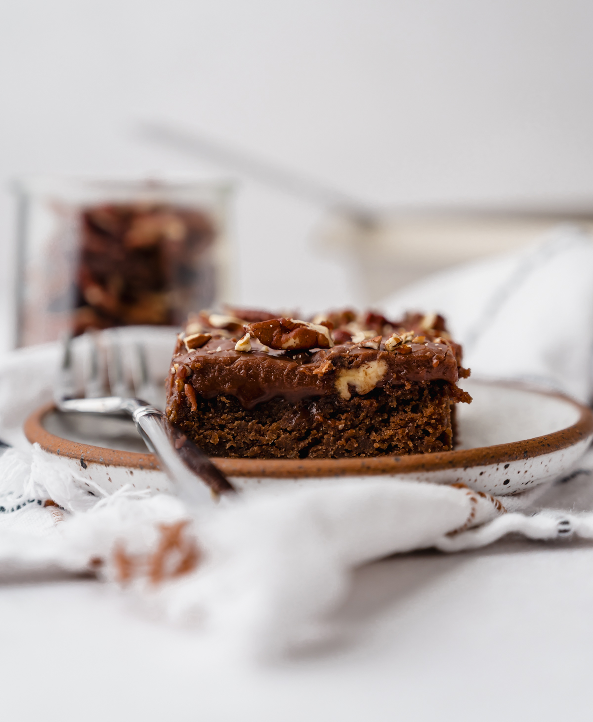 A slice of chocolate Texas sheet cake on a plate with a fork.
