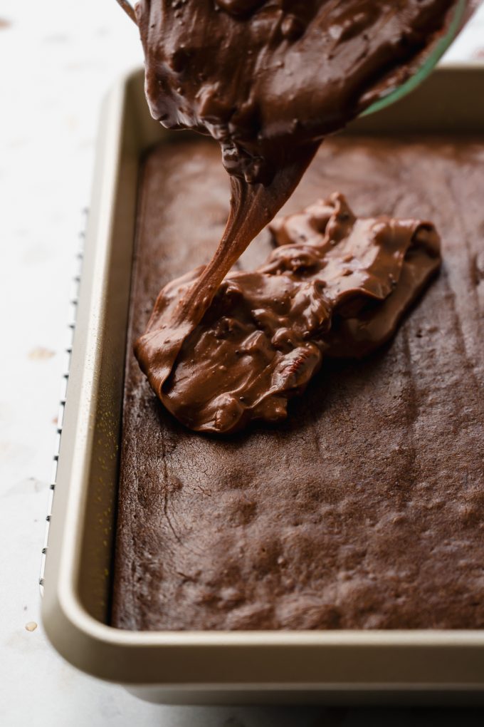 Someone is pouring chocolate icing onto a baked chocolate Texas sheet cake.