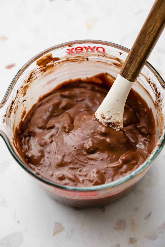 A glass measuring cup with ingredients to make the chocolate icing for Texas sheet cake.