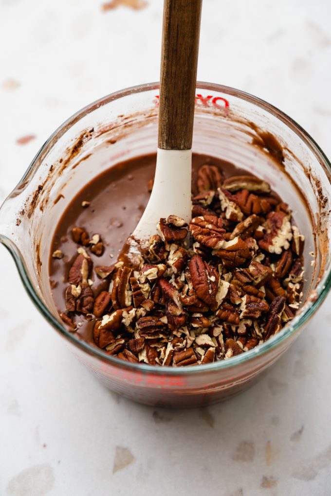 A glass measuring cup with ingredients to make the chocolate icing for Texas sheet cake.
