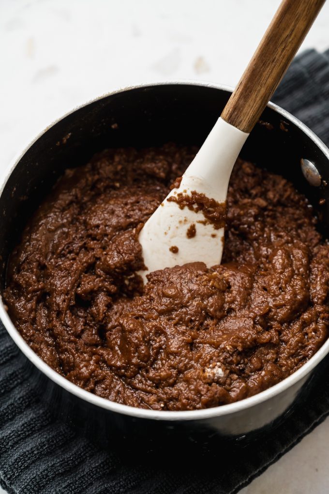 A saucepan of a mixture for the batter of a Texas sheet cake being stirred together with a spatula.