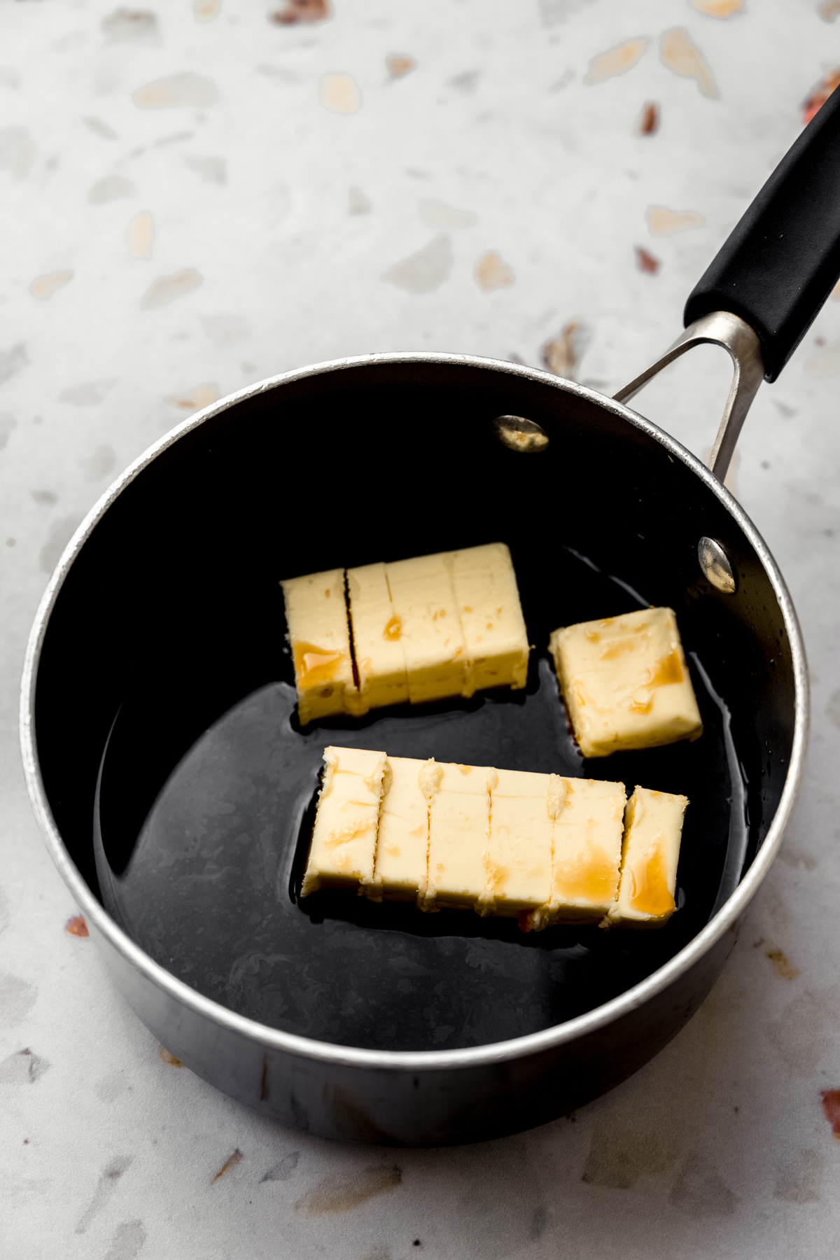 A saucepan with coffee and slices of butter in it.