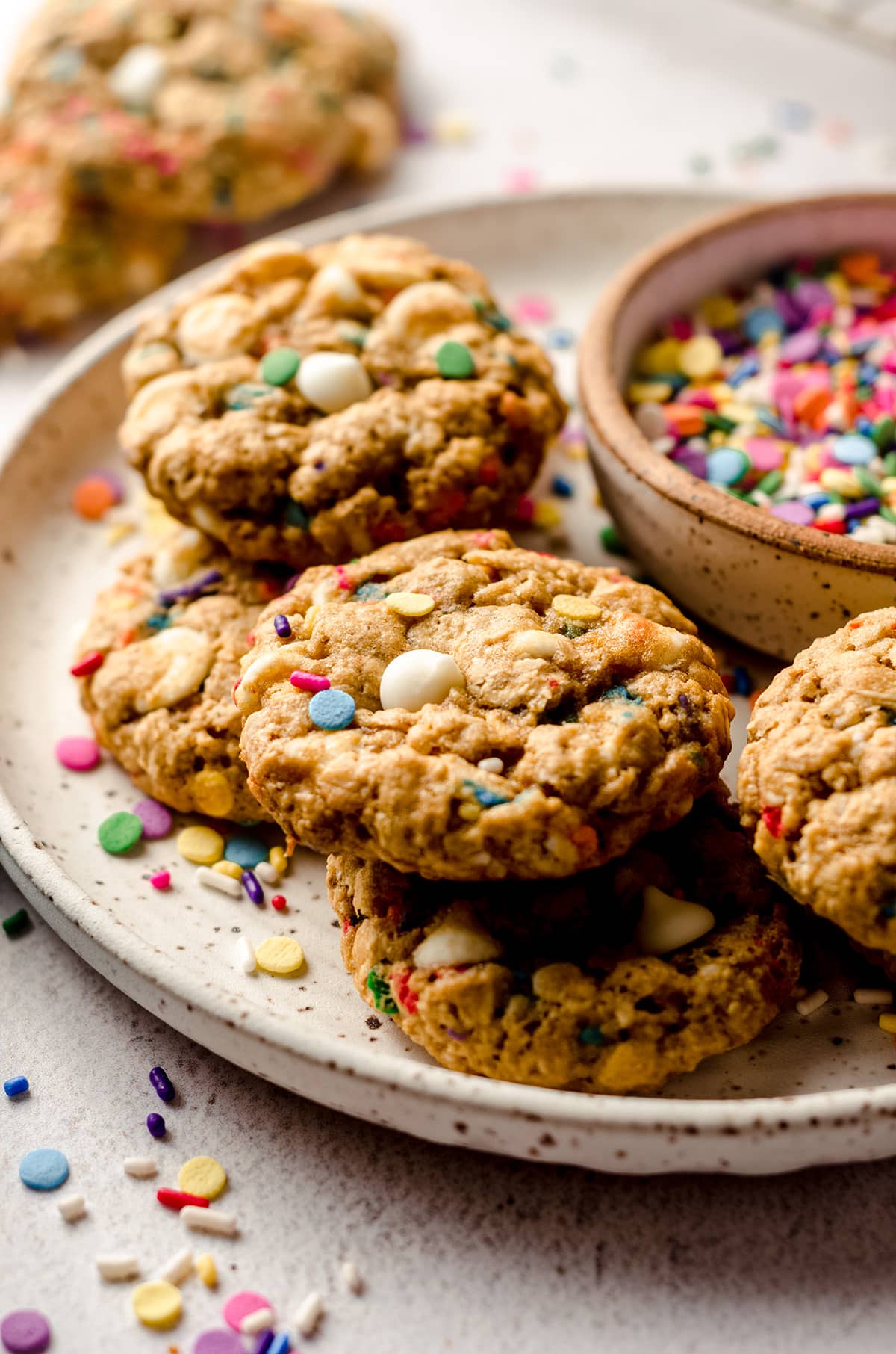 funfetti oatmeal cookies on a plate with a bowl of sprinkles