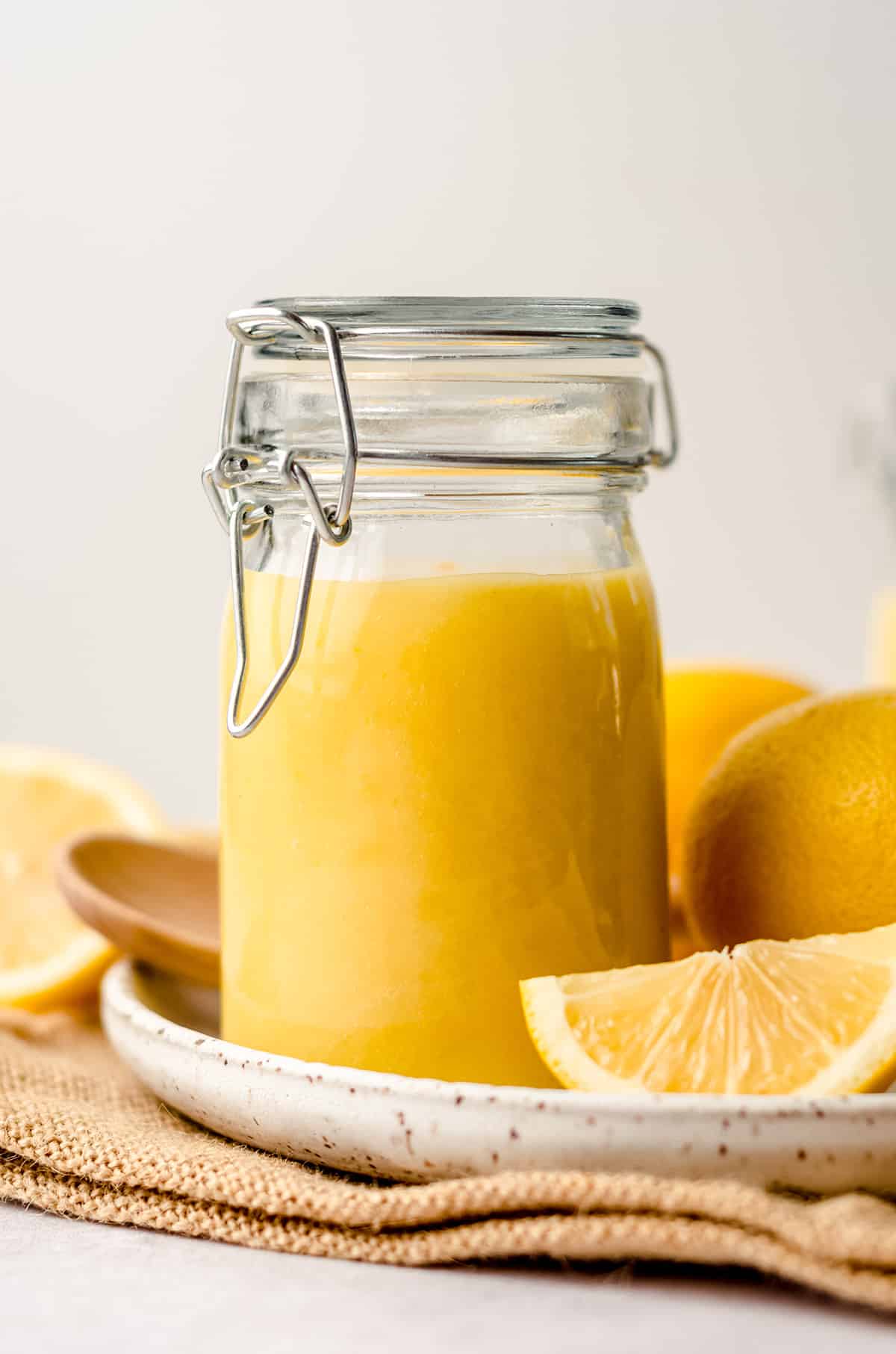 a jar of lemon curd on a plate with lemons