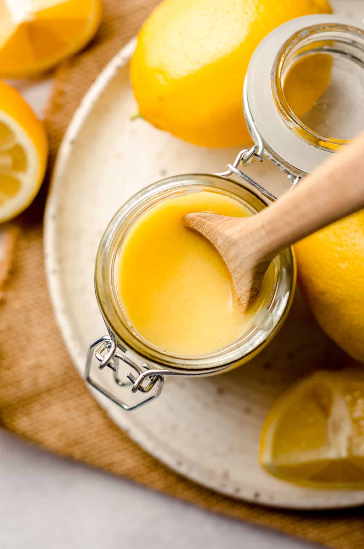 aerial photo of jar of lemon curd with a wooden spoon in it