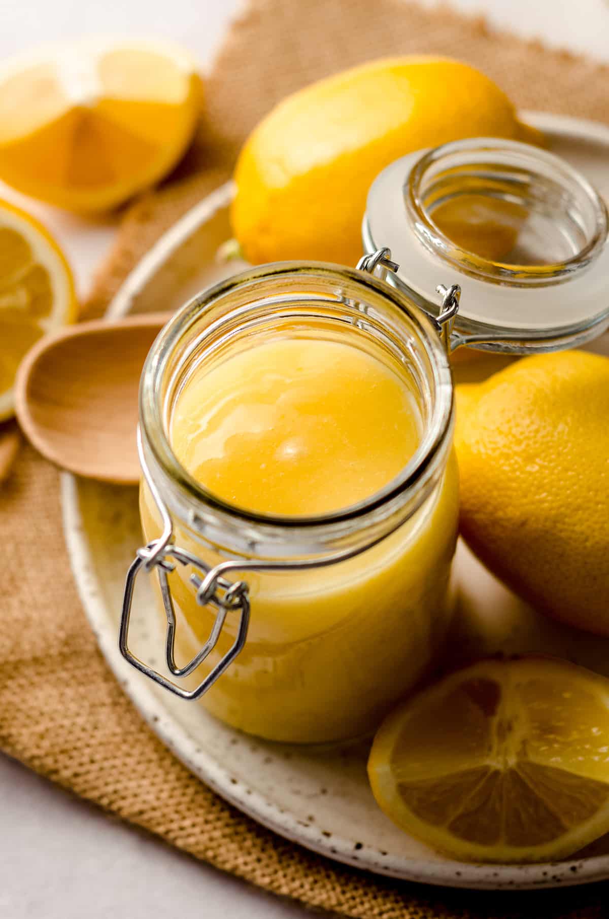 a jar of lemon curd on a plate with lemons