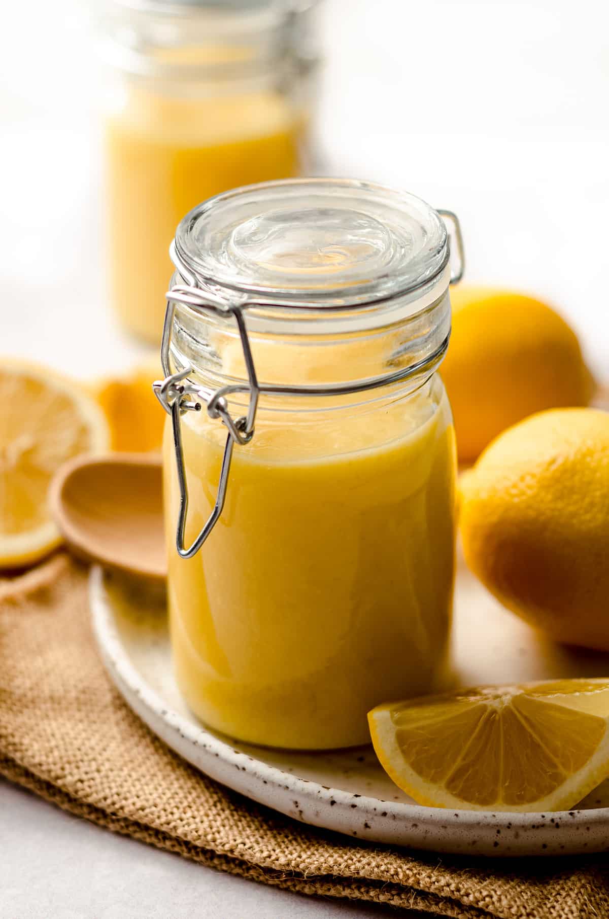 a jar of lemon curd on a plate with lemons
