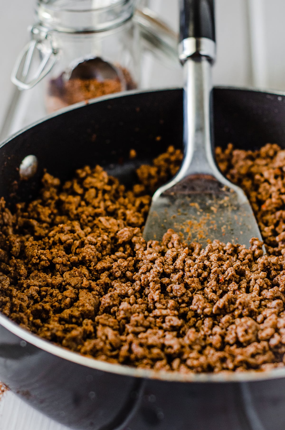 browned and seasoned taco meat in a skillet with a spatula