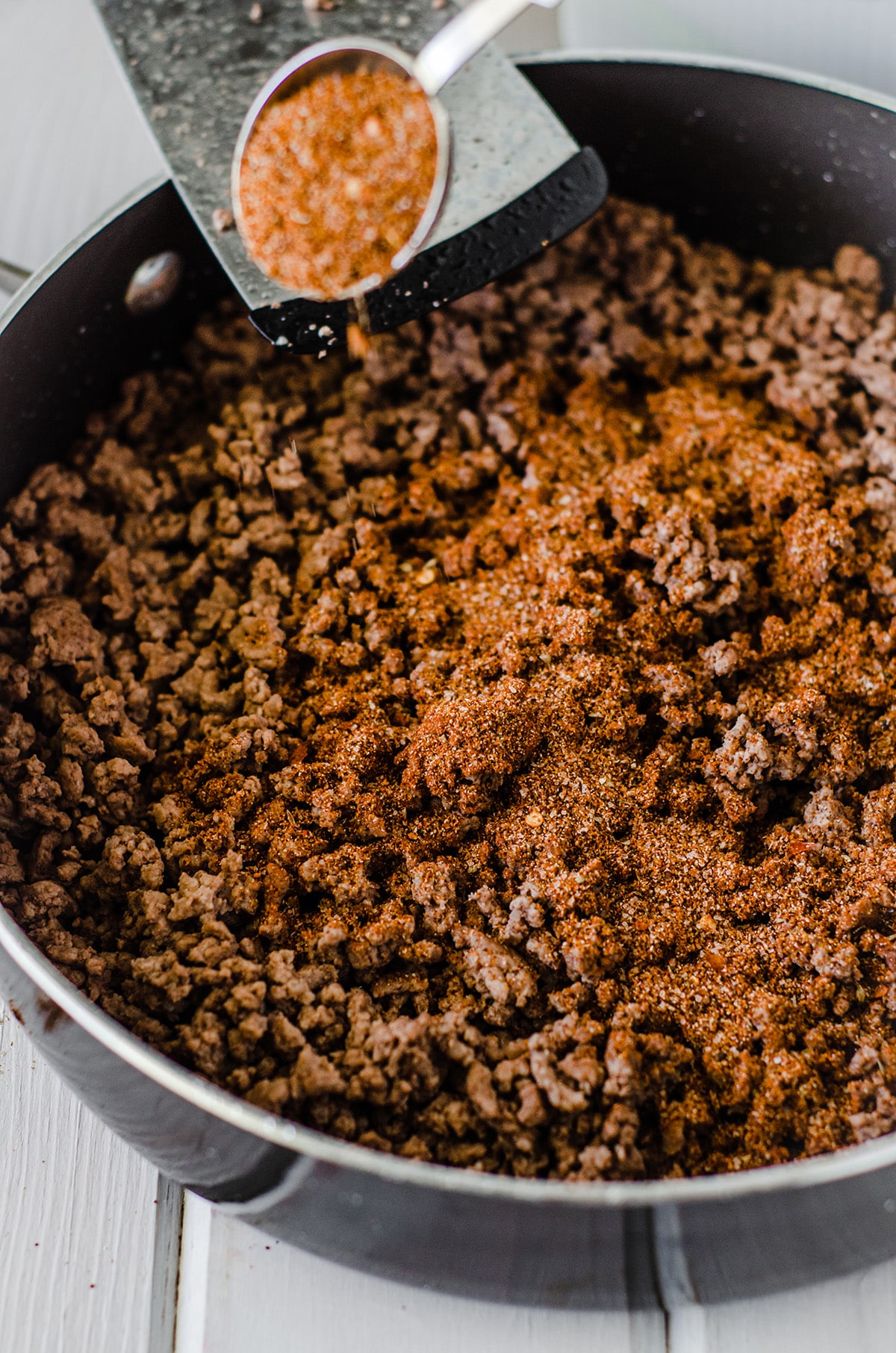 sprinkling homemade taco seasoning on browned meat