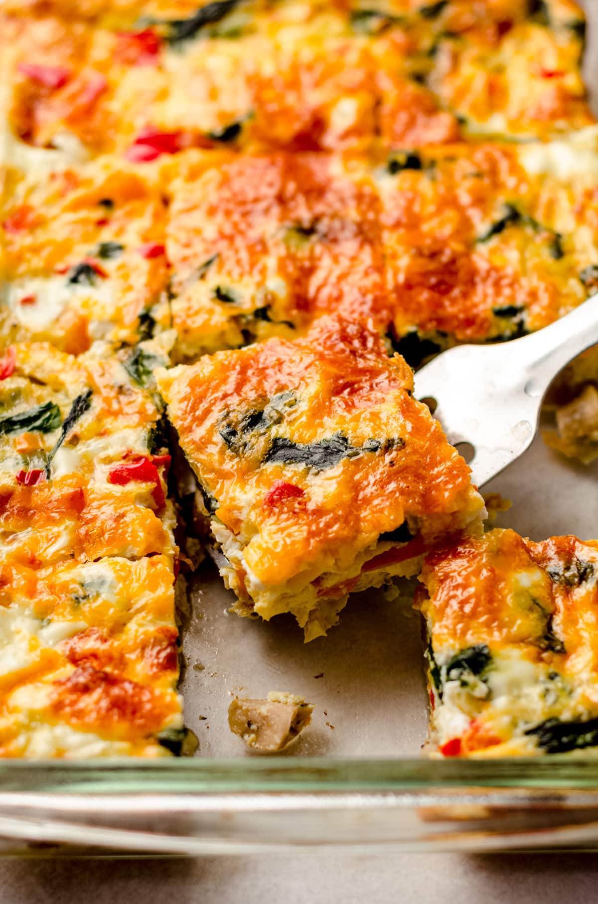 freezer breakfast casserole sliced in a dish and a spatula is taking a slice out to serve it