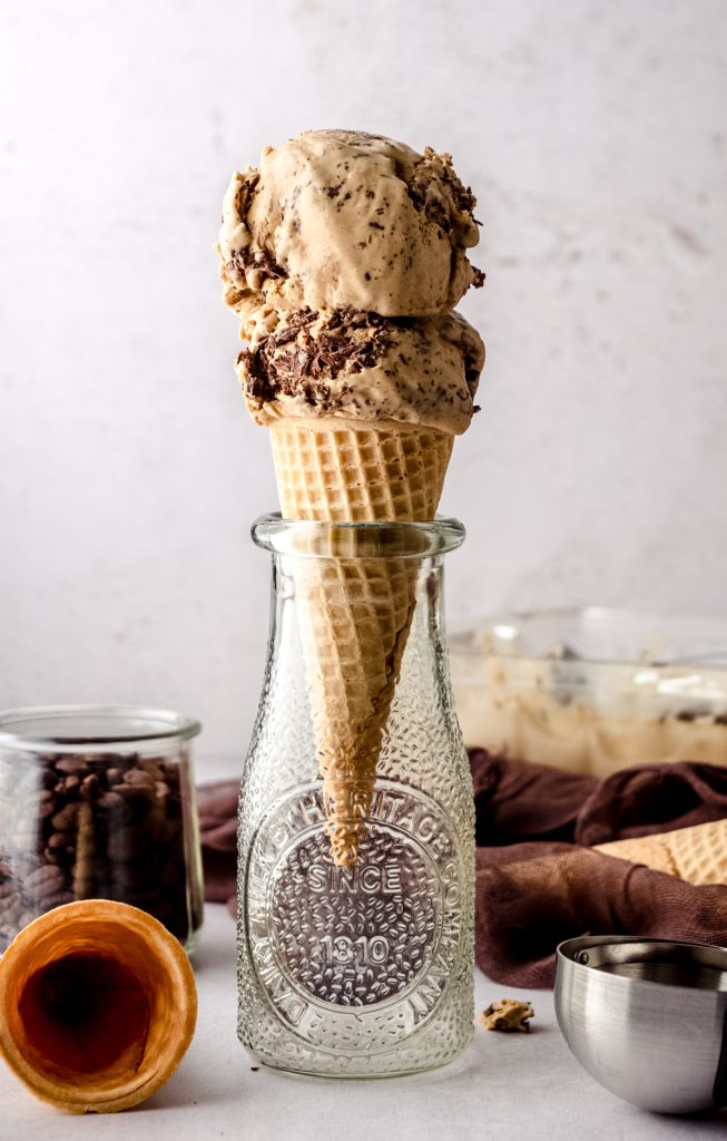Two scoops of coffee ice cream in a cone sitting in an empty milk bottle.