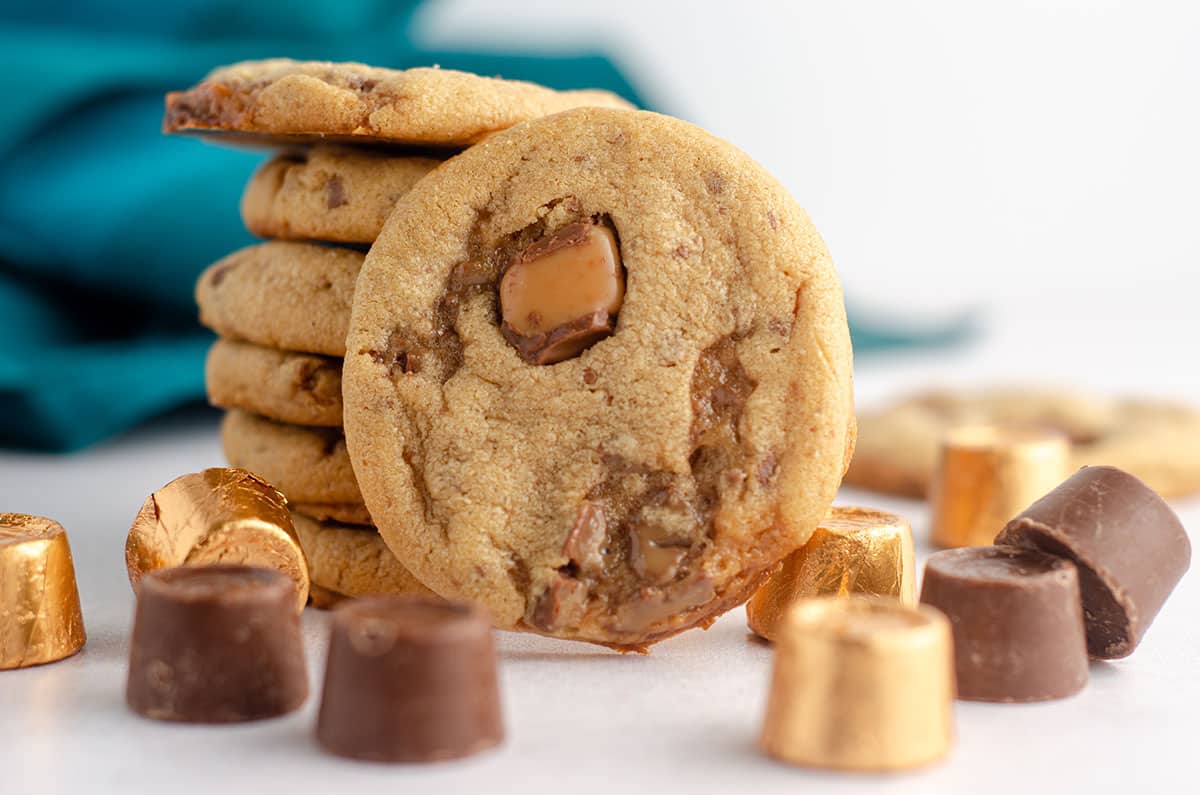 peanut butter rolo cookie sitting in front of a stack of cookies with scattered rolos