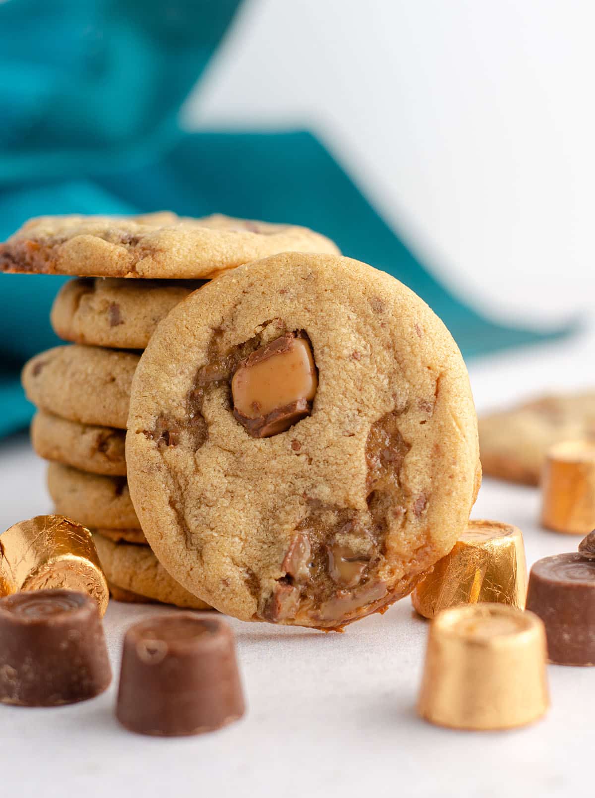 peanut butter rolo cookie sitting in front of a stack of cookies with scattered rolos